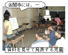 資料を見せて発表する児童