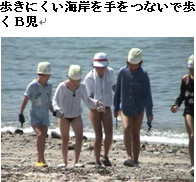 歩きにくい海岸を手をつないで歩くB児の写真