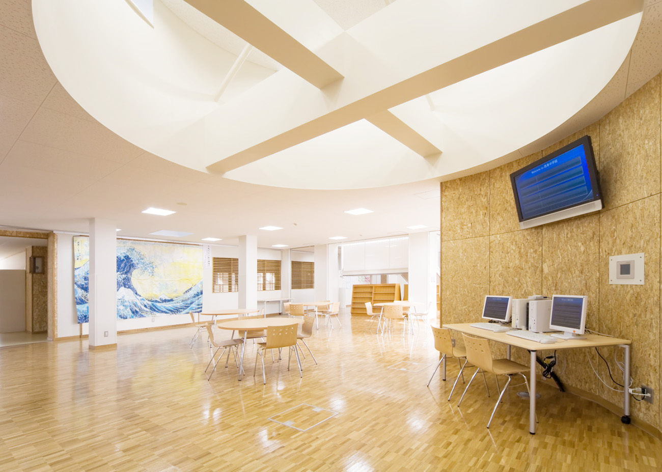 メディアセンターの写真。天井は吹き抜けになっており、明るい雰囲気で、椅子やテーブル、PCが設置されている。
