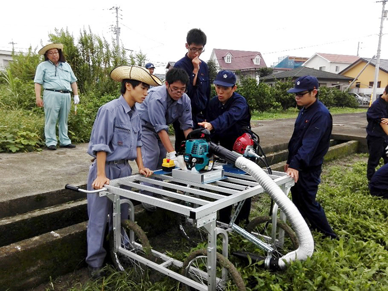 藍の刈り取り機を試運転する城西高校と徳島科学技術高校の生徒（県央部）＝徳島市の城西高校ほ場